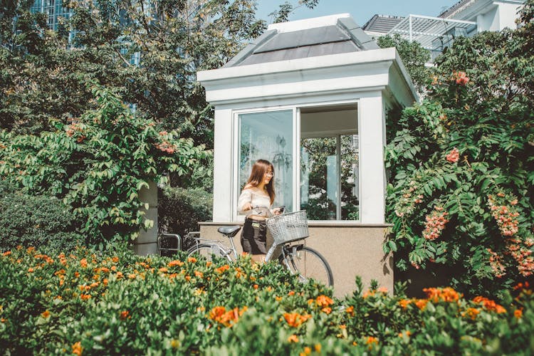 Woman Leading Bicycle In Garden