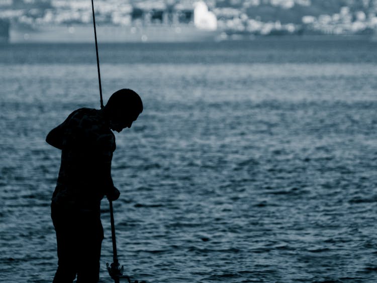 Silhouette Of Man Holding A Fishing Rod