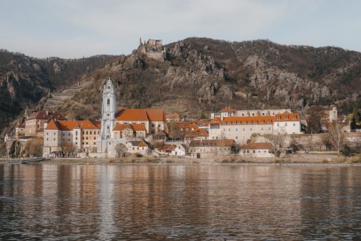 Picturesque view of Dürnstein Abbey on a hill by the Danube River surrounded by historic architecture.
