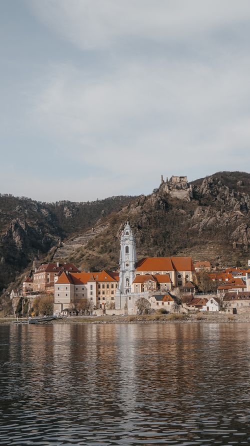 Free Scenic view of a medieval town with church and mountains by the river. Stock Photo