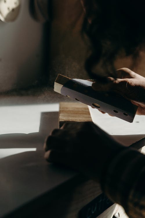 A Person Holding a Small Wood with Sandpaper