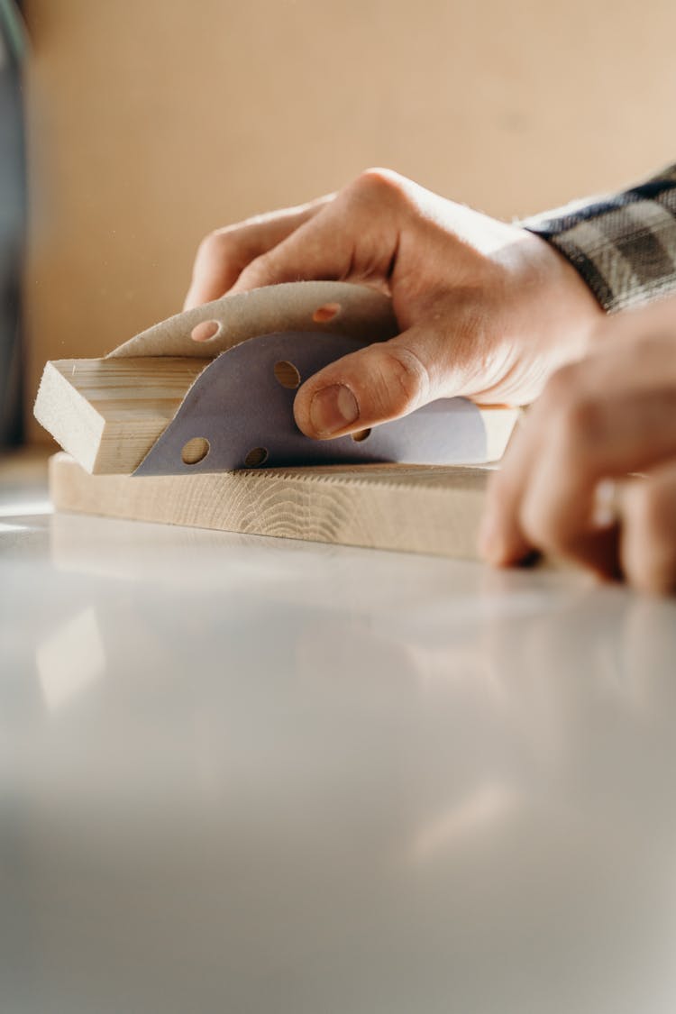 A Person Using A Sandpaper On A Piece Of Wood