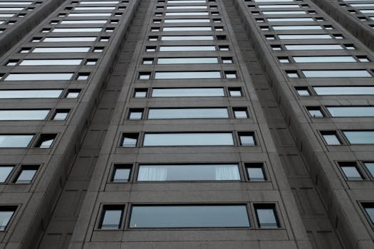 Low-angle view of a modern high-rise building with concrete facade and glass windows.