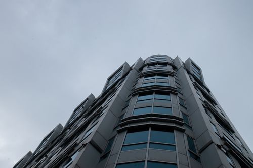 Free Low-angle perspective of a modern skyscraper with glass windows against overcast sky. Stock Photo