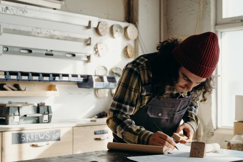 Free A craftsman deeply focused on a woodworking project in a well-lit workshop environment. Stock Photo