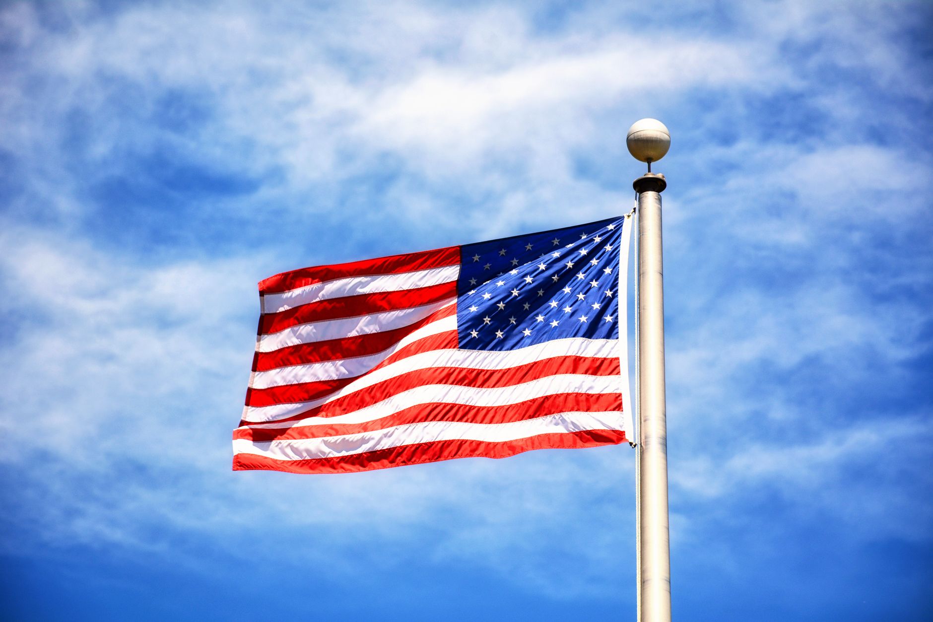 Vibrant American flag flying against a clear blue sky, symbolizing freedom and patriotism.
