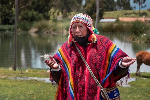 An elderly man wearing vibrant traditional Peruvian clothing near a scenic lake in Cusco, Peru.