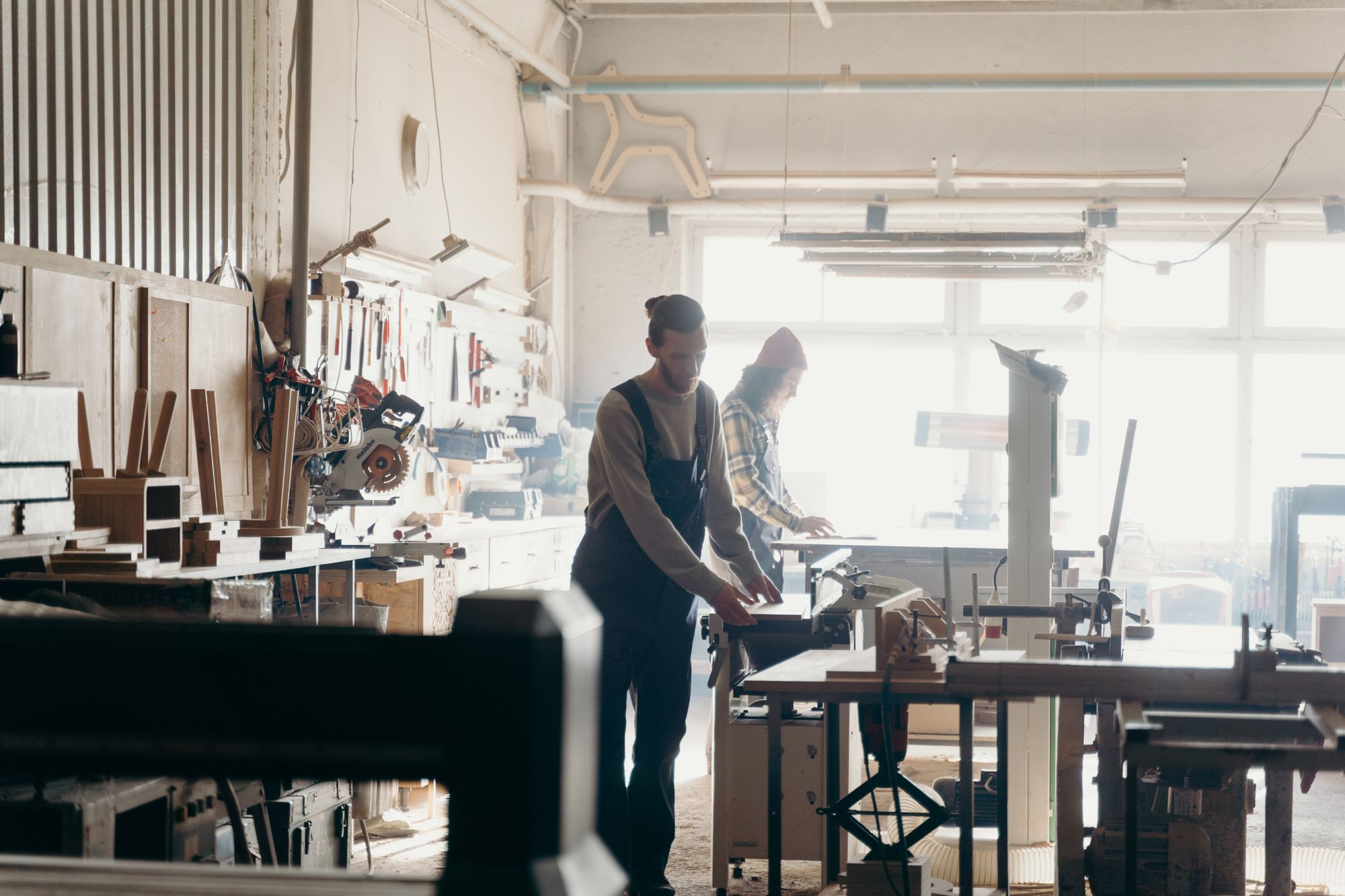 An open studio floor of workbenches in a daylit maker's workshop — photo by cottonbro studio on Pexels