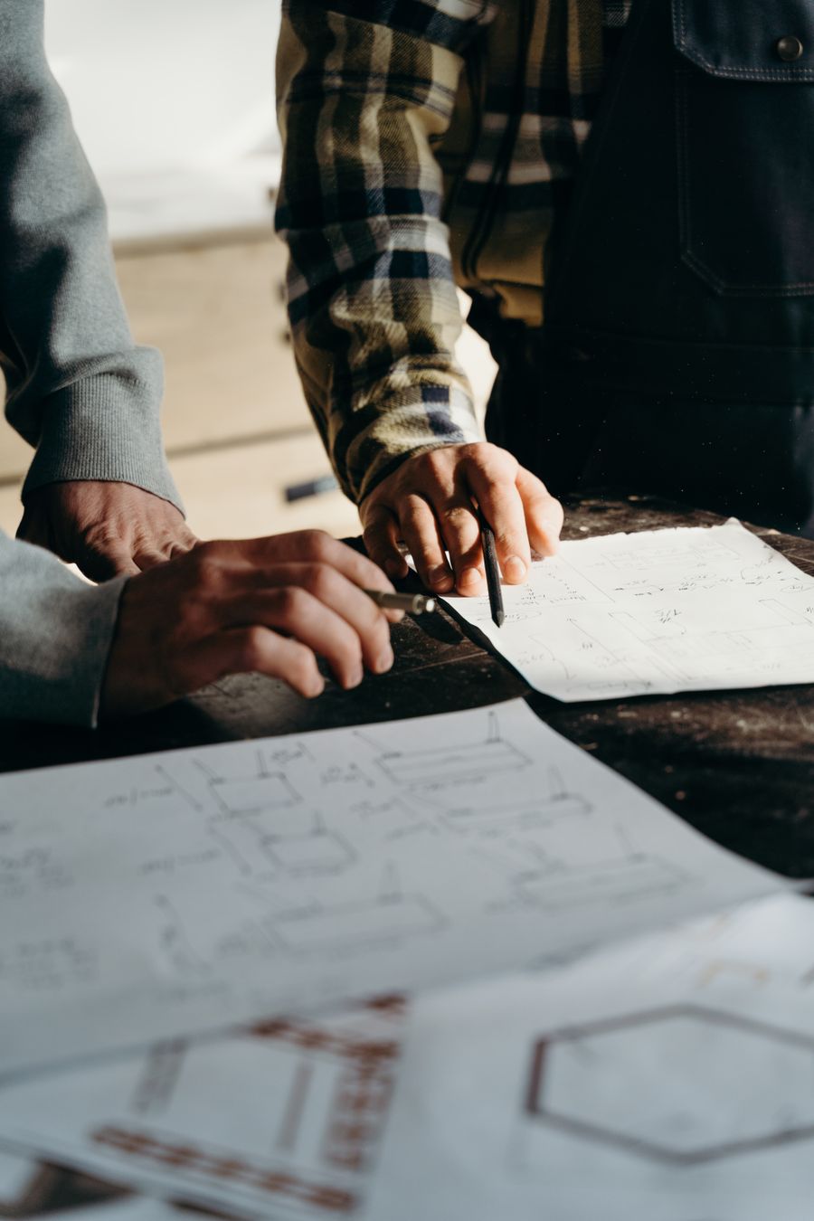 Manos trabajando sobre planos técnicos en un taller de producción