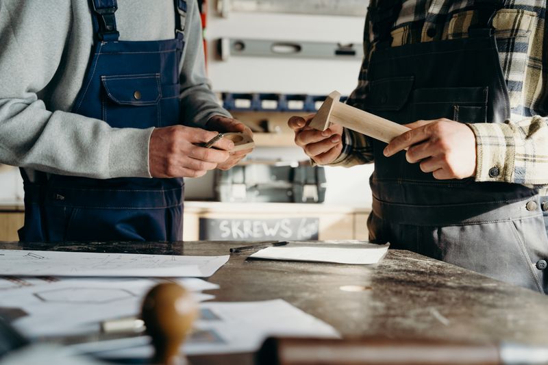 Two makers comparing notes over a bench in the finishing room — cottonbro studio on Pexels