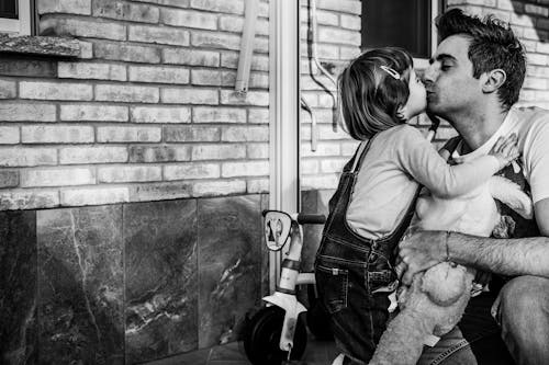 Monochrome Photo of a Father Kissing His Daughter