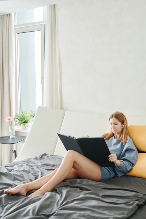 Woman Lying on Bed While Holding a Book