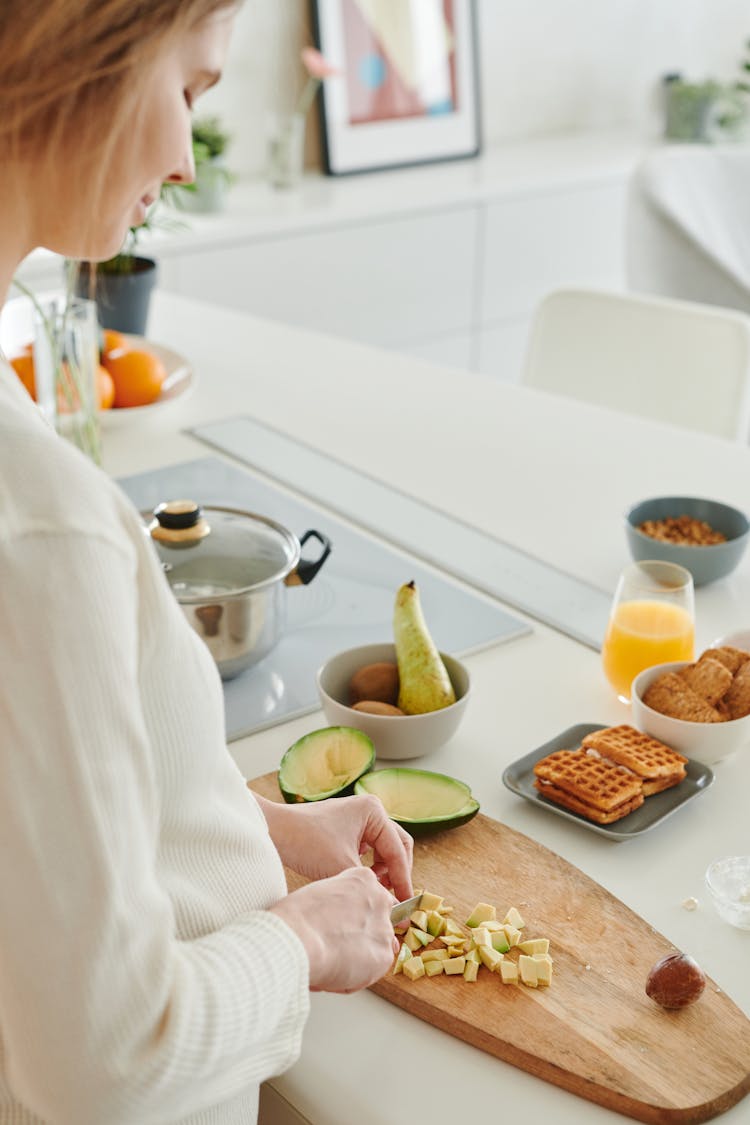 Person Slicing Food On Wooden Chopping Board