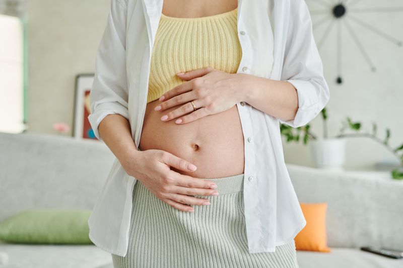 Femme enceinte tenant son ventre arrondi avec tendresse, représentant le bien-être maternel durant la grossesse