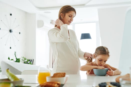 A pregnant mother helps her daughter with breakfast at home in a bright kitchen.
