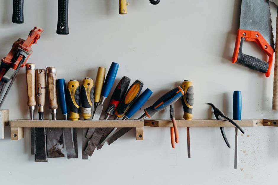 A neatly arranged collection of hand tools including chisels, saws, and screwdrivers in a workshop.
