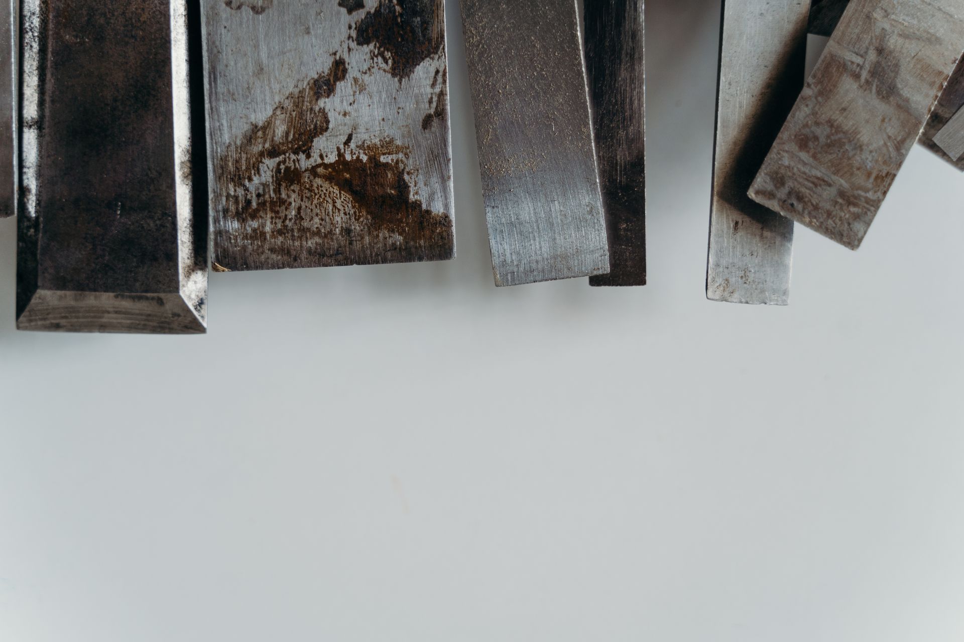 An abstract still life of textured metal pieces on a white surface.