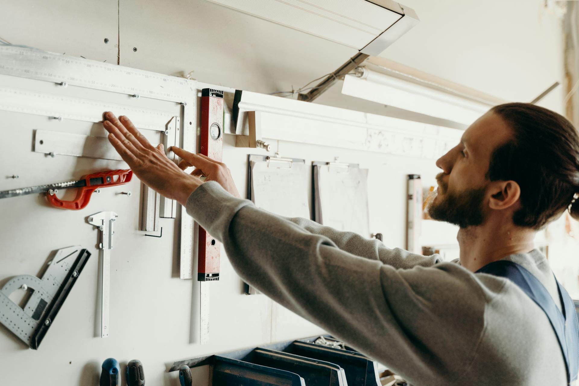 A Man Fixing Carpentry Tools Hanging  on the Wall