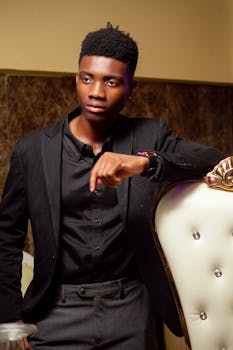 Portrait of a fashionable young man in a black suit, posing confidently indoors.