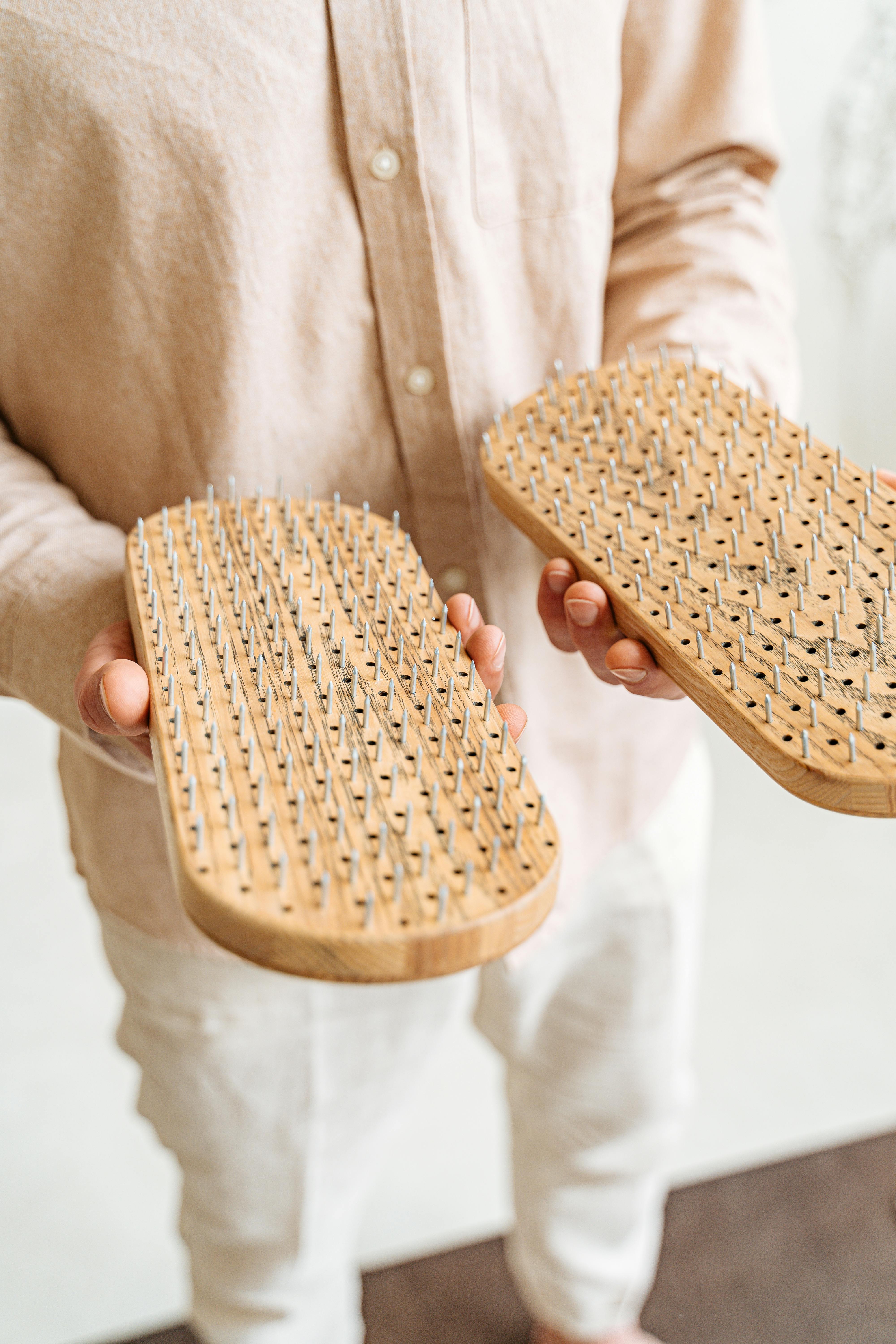 Close-up of hands holding a wooden sadhu board with metal nails for meditation.