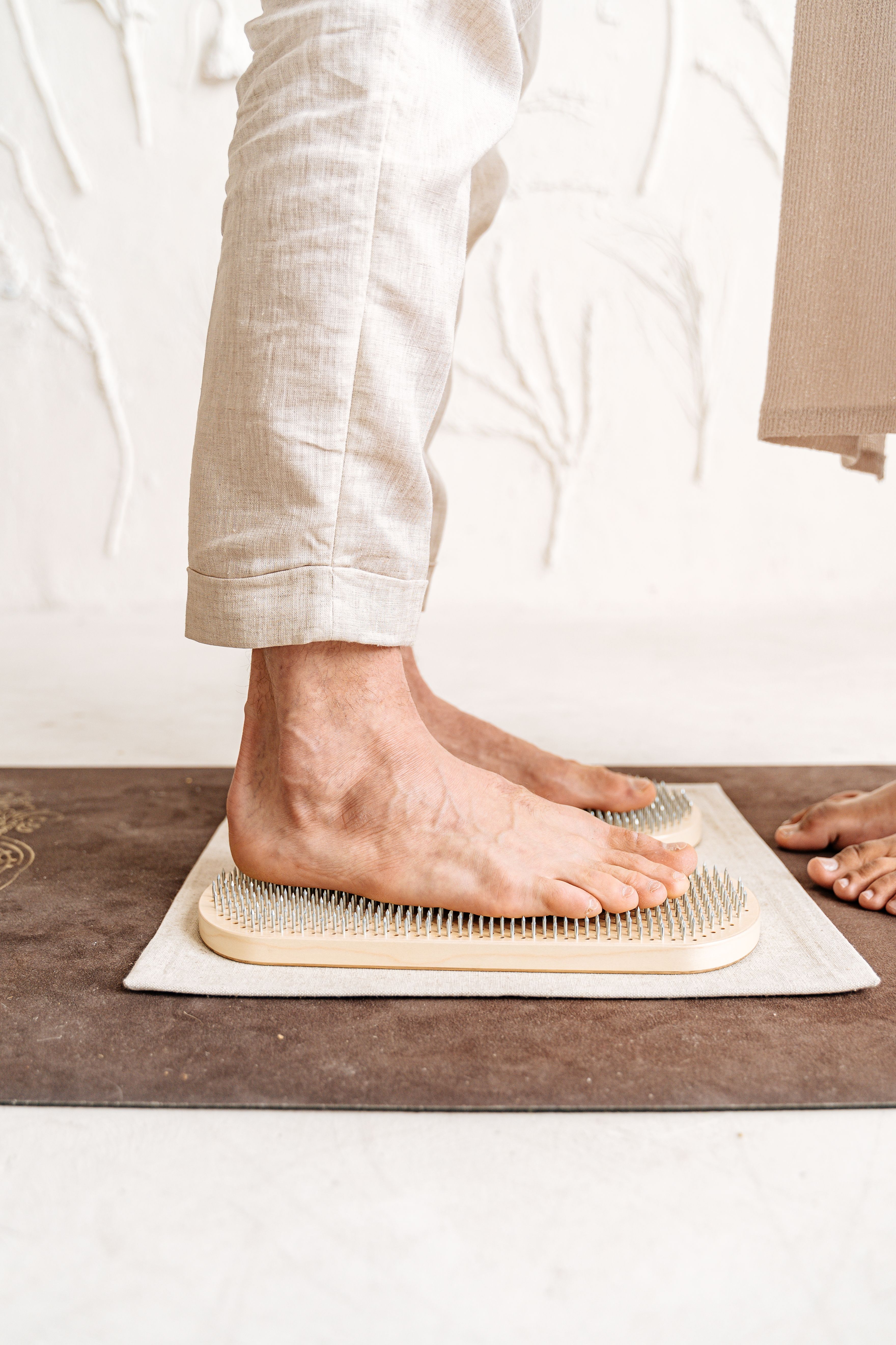 Close-up of a person standing barefoot on a Sadhu board, showcasing alternative therapy practice.