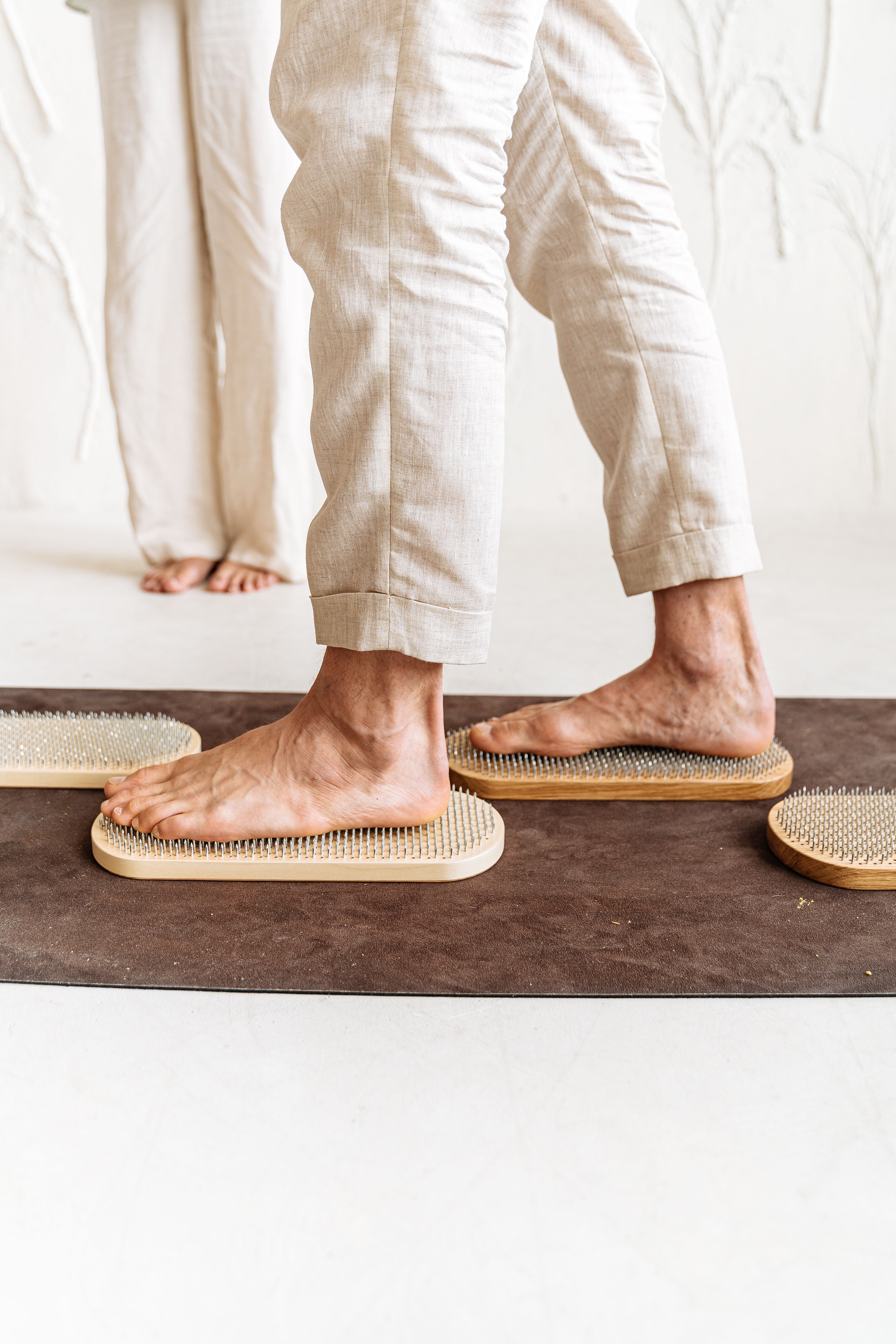 Close-up of individuals using acupressure mats for foot therapy in a calm indoor setting.