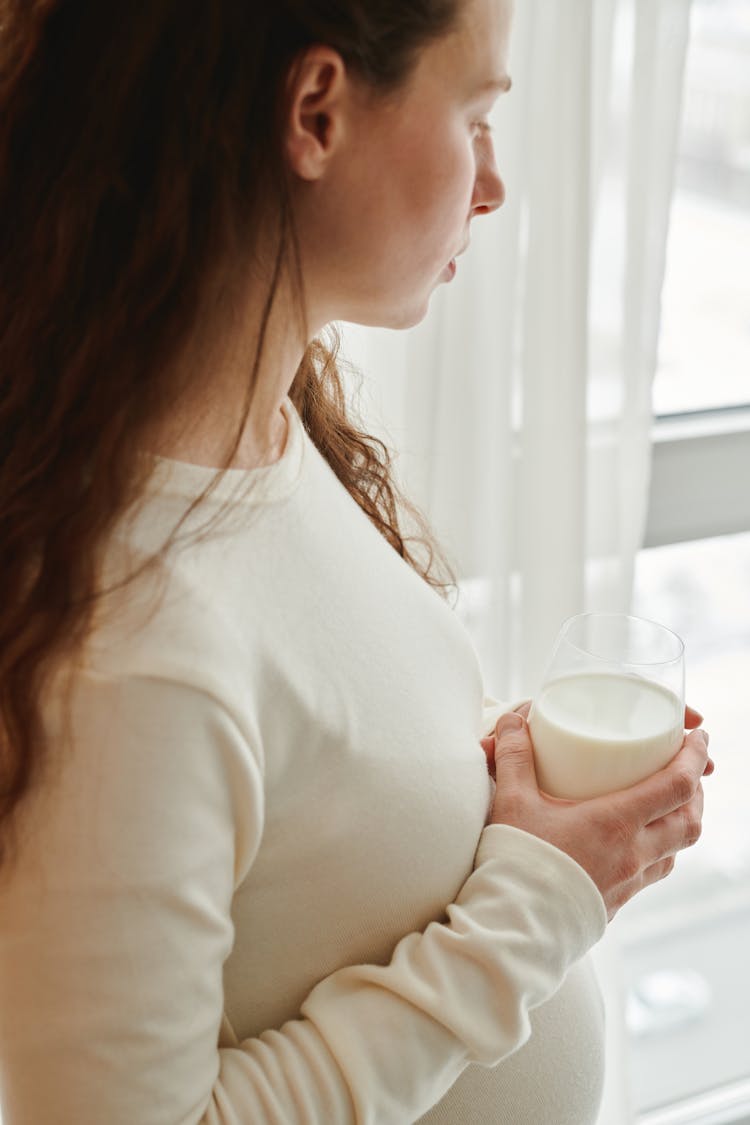 A Pregnant Woman Holding A Glass Of Milk 