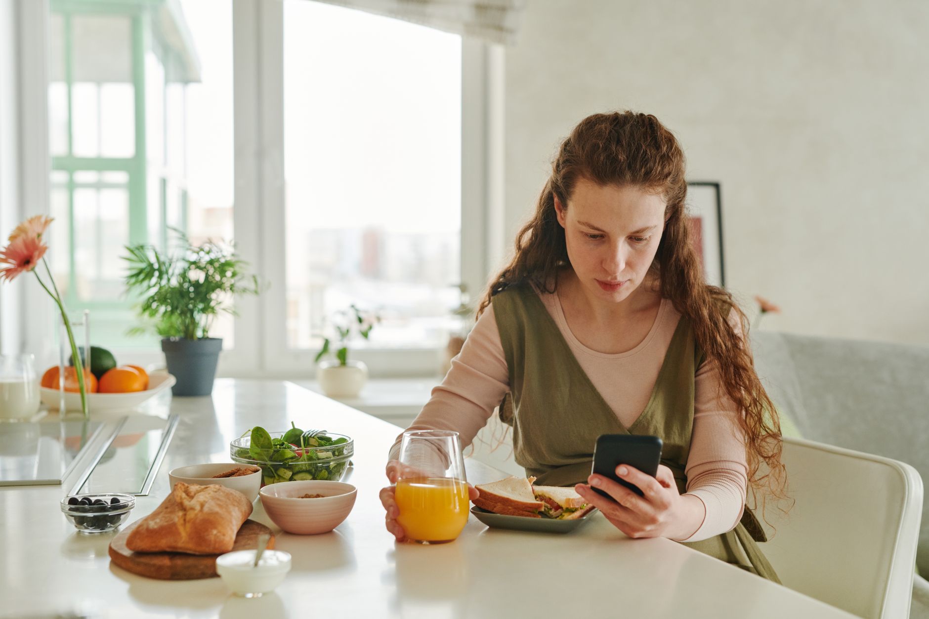 A person checking a calendar notification on their phone at a kitchen table, the kind of reminder that prevents a missed coaching session