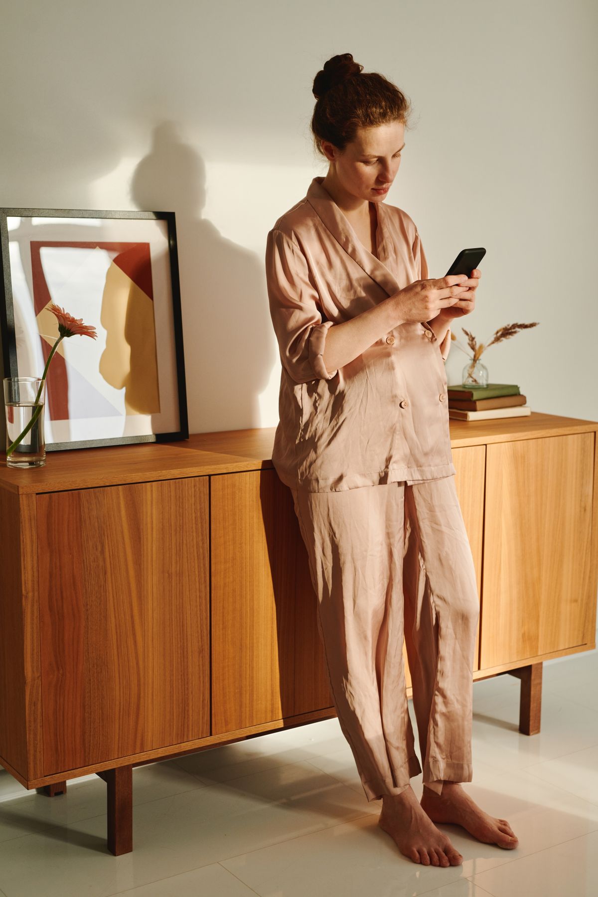 Pregnant woman using a smartphone in a comfortable home setting