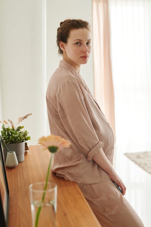 A Pregnant Woman Leaning on a Wooden Surface