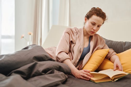 Free Woman Reading Book on Bed Stock Photo