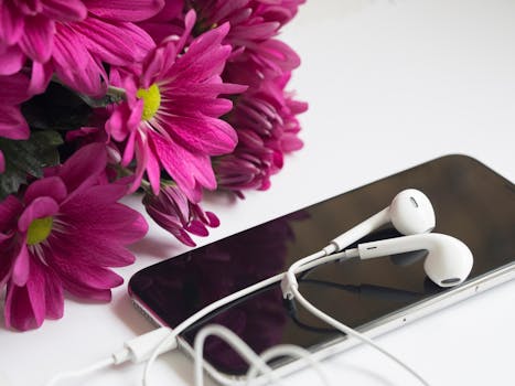 粉红色花朵的特写镜头，搭配智能手机和耳机的现代审美
