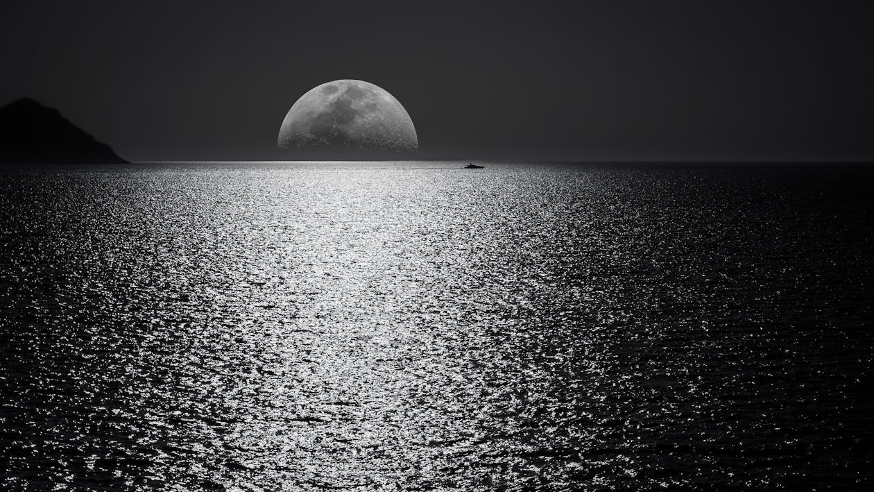 Free White and Black Moon With Black Skies and Body of Water Photography during Night Time Stock Photo