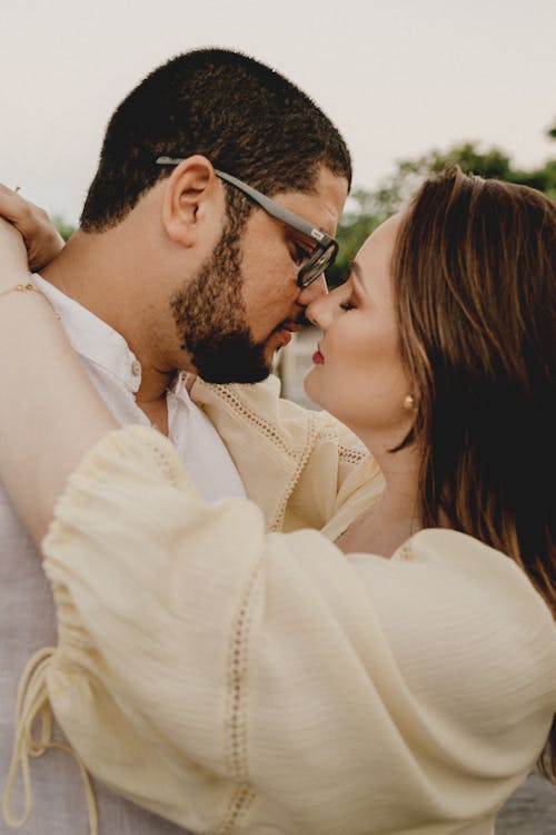 Side view of gentle girlfriend with closed eyes embracing unshaven boyfriend in eyeglasses while spending romantic time together