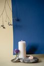 White Pillar Candle on Blue Wall