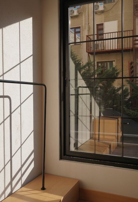 A modern interior scene featuring sunlight casting geometric shadows through a window with a view outside.