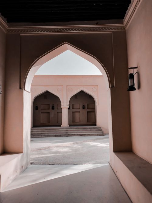 Free Captivating view of an arched hallway in an Islamic architectural structure with sunlight streaming through. Stock Photo