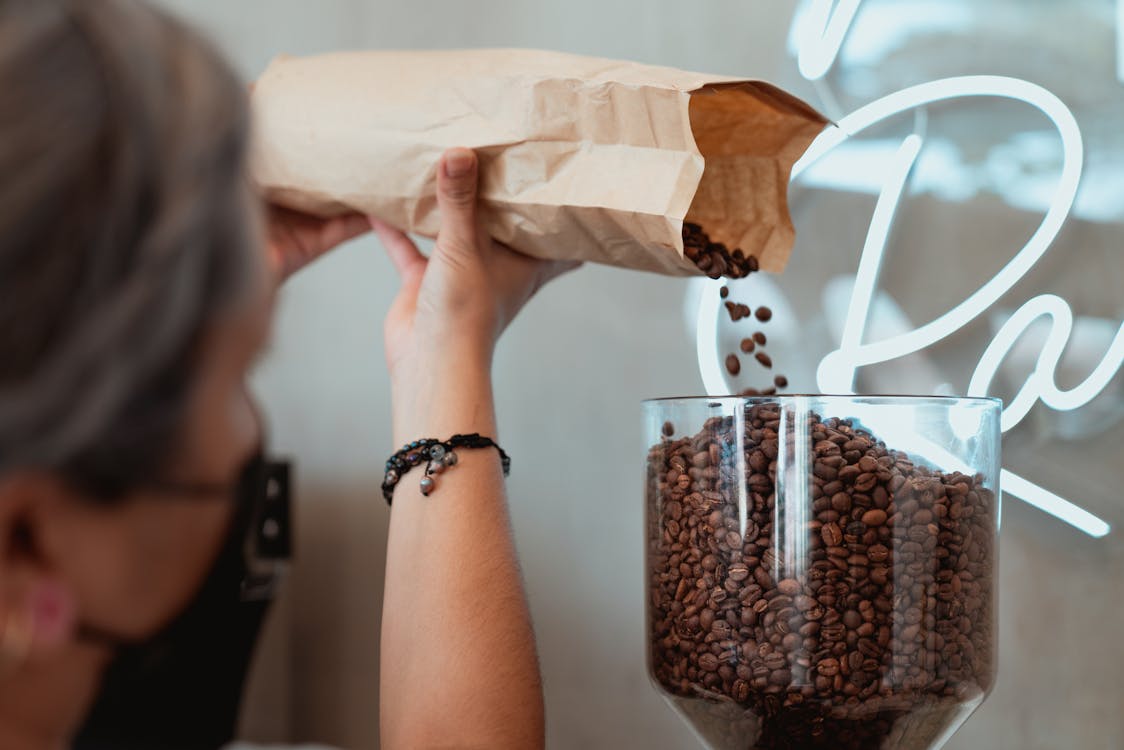 Photo of Barista Pouring Fresh Coffee Beans on Coffee Grinder