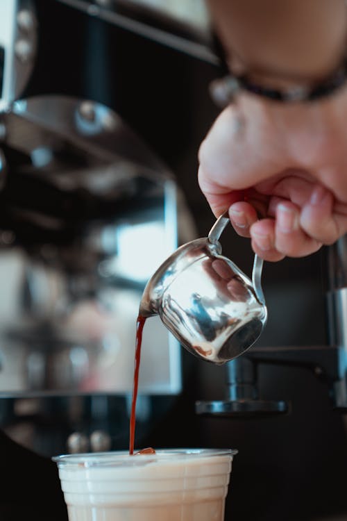 Free Photo of Person Pouring Espresso on a Disposable Glass of Milk Stock Photo