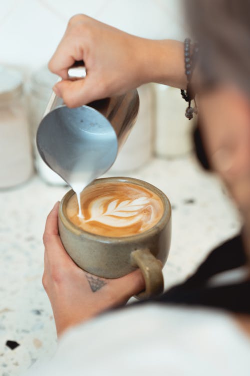 Free Photo of Person Pouring Milk on a Cup of Latte Stock Photo