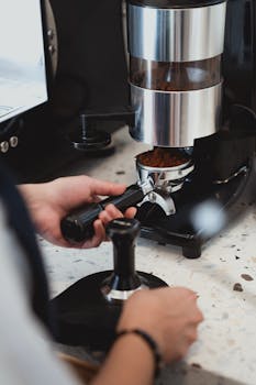 Close-up of a barista grinding coffee beans for a fresh brew. Perfect for coffee enthusiasts.