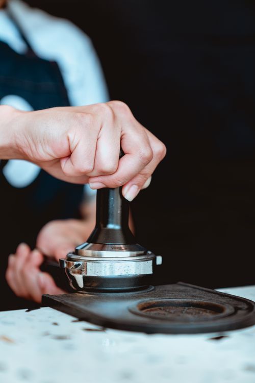 Free Close-up of barista crafting espresso with a portafilter in a modern cafe setting. Stock Photo