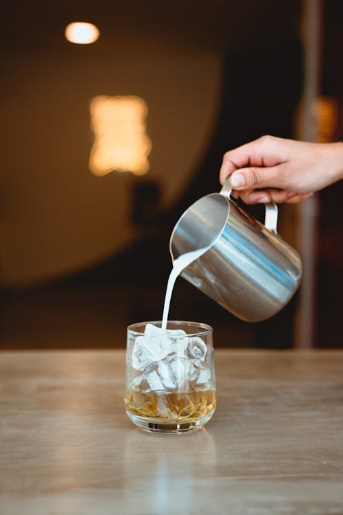 Phot of Person Pouring Water on Glass with Ice