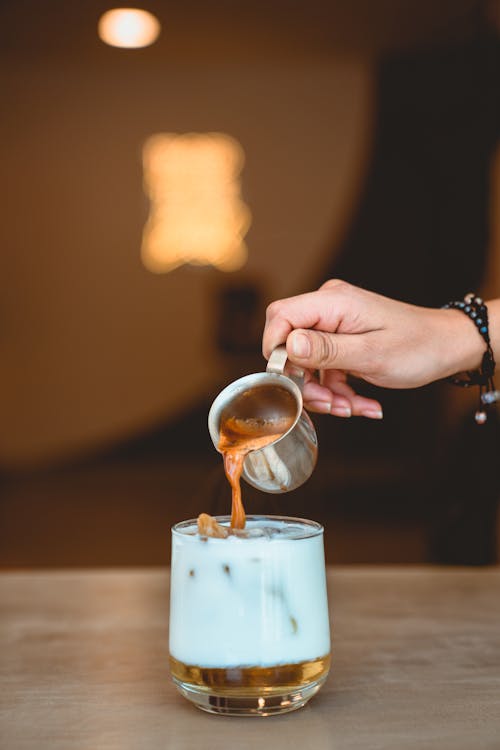 Free Photo of Person Pouring Espresso on Glass with Milk Stock Photo