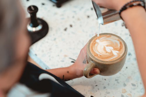 Photo of Barista Pouring Milk on Latte