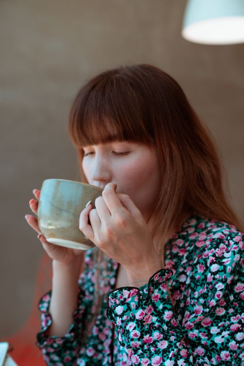 Free A woman savoring a cup of coffee inside a cozy setting, embracing relaxation. Stock Photo