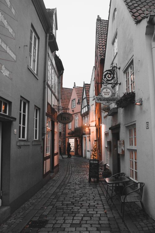Free A picturesque narrow alleyway in Europe with cobblestone pavement and historic architecture, lighting up at dusk. Stock Photo