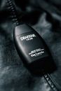 From above of black plastic bottle of men fragrance placed on black leather surface