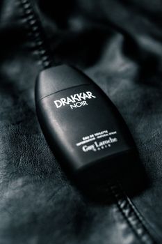 From above of black plastic bottle of men fragrance placed on black leather surface