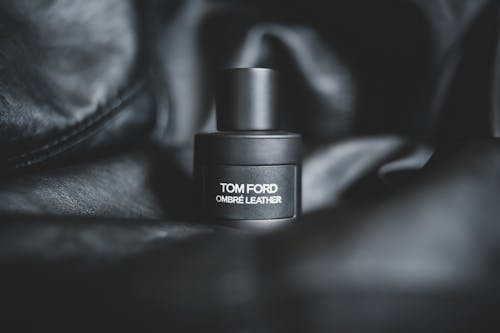 Closeup of black plastic bottle with expensive fragrance placed on black leather material
